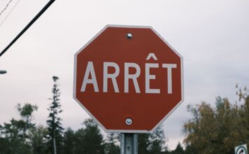 Close-up of a red French stop sign outdoors with trees in the background.