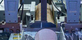 Close-up of an industrial machine cutting a metal rod with precision.