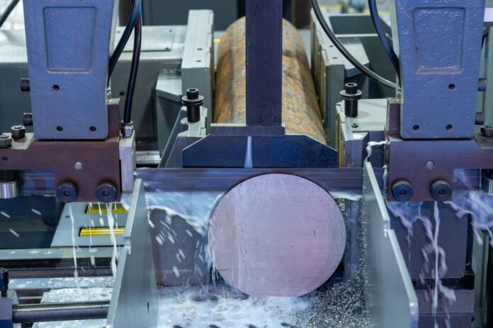 Close-up of an industrial machine cutting a metal rod with precision.