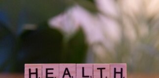 Close-up of Scrabble tiles spelling 'Health' on a wooden table with a blurred background.