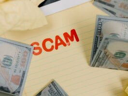 Conceptual image of financial scam with US dollars on yellow paper and word 'scam' visible.