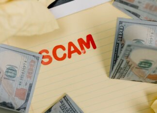 Conceptual image of financial scam with US dollars on yellow paper and word 'scam' visible.
