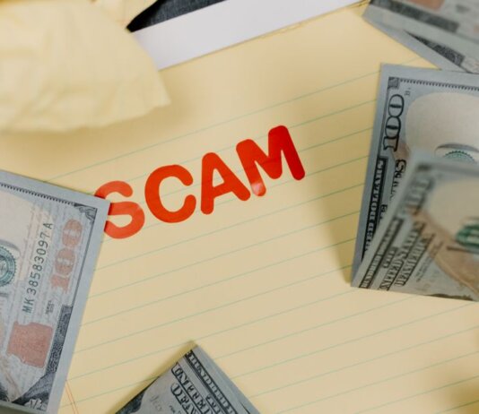 Conceptual image of financial scam with US dollars on yellow paper and word 'scam' visible.