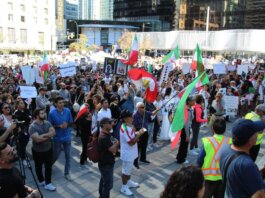 Crowd in Vancouver holding signs and flags in a peaceful protest for human rights.