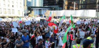 Crowd in Vancouver holding signs and flags in a peaceful protest for human rights.