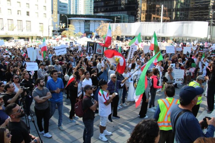 Crowd in Vancouver holding signs and flags in a peaceful protest for human rights. Crowd in Vancouver holding signs and flags in a peaceful protest for human rights.
