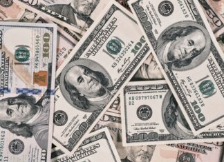 Путешествия важнее быта: исследование Booking.com о приоритетах туристов Detailed close-up of US dollar bills highlighting wealth and finance concepts.