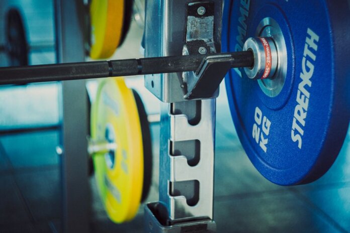 Detailed view of 20 kg weights on a barbell in a gym, emphasizing strength and fitness. Detailed view of 20 kg weights on a barbell in a gym, emphasizing strength and fitness.