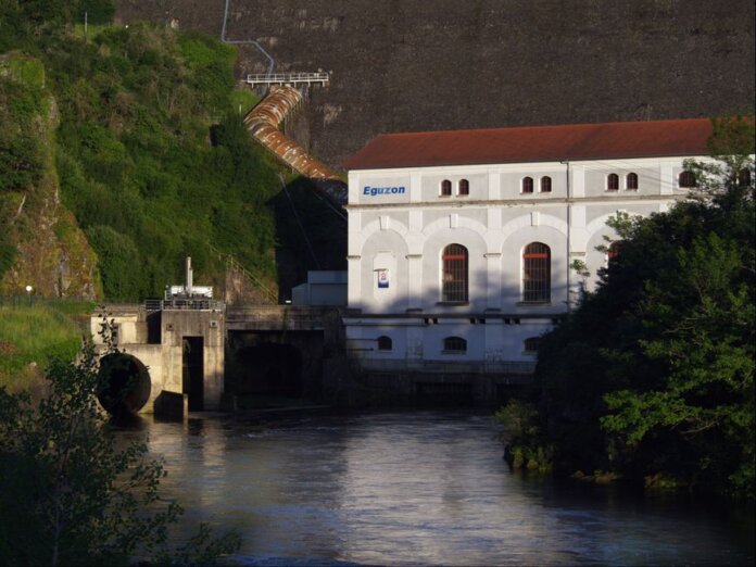 Eguzon hydroelectric plant by a river during sunset, surrounded by lush greenery. Eguzon hydroelectric plant by a river during sunset, surrounded by lush greenery.