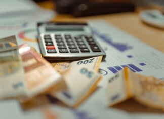 Euro banknotes and calculator on financial documents, focusing on business budget planning.