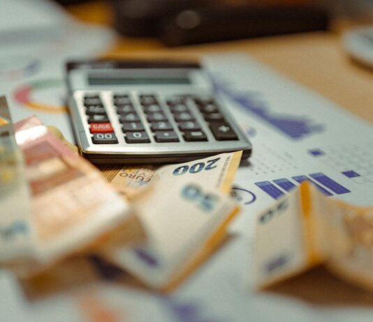 Euro banknotes and calculator on financial documents, focusing on business budget planning.