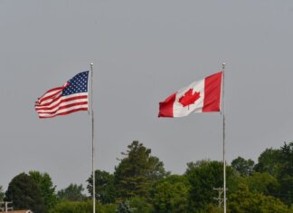 Министр Ананд встретилась с госсекретарём США Марко Рубио Flags of the USA and Canada waving on flagpoles against a clear sky in Sarnia, Ontario.