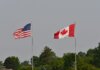 Министр Ананд посетит Вашингтон для обсуждения приоритетов Канады Flags of the USA and Canada waving on flagpoles against a clear sky in Sarnia, Ontario.