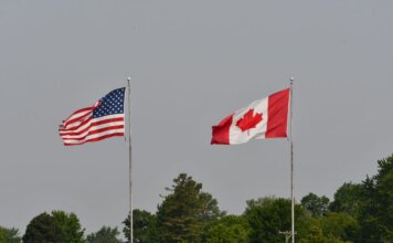 Министр Ананд посетит Вашингтон для обсуждения приоритетов Канады Flags of the USA and Canada waving on flagpoles against a clear sky in Sarnia, Ontario.