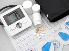Flat lay of blood pressure monitor, pills, and ECG printout for heart health theme.