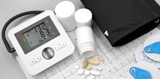 Flat lay of blood pressure monitor, pills, and ECG printout for heart health theme.