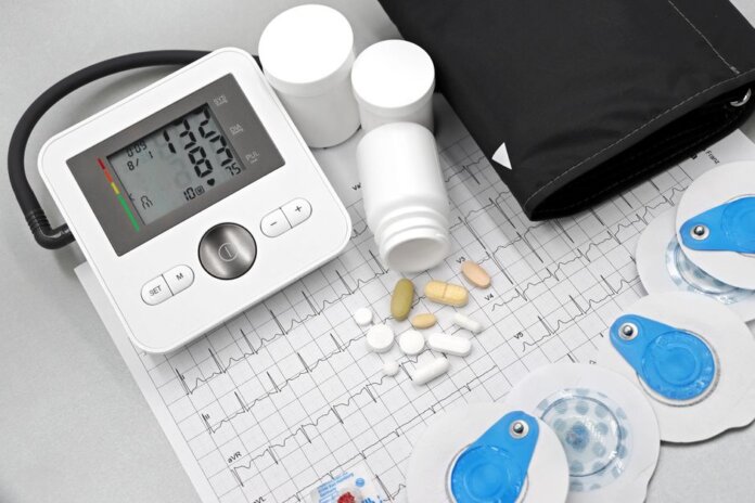 Flat lay of blood pressure monitor, pills, and ECG printout for heart health theme. Flat lay of blood pressure monitor, pills, and ECG printout for heart health theme.