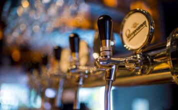 Focused image of a shiny beer tap in a stylish bar with a blurred background.