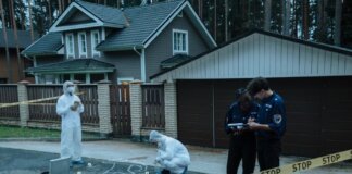 Forensic team investigates suburban crime scene with police officers and evidence markers.