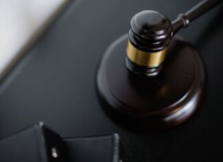 From above of wooden gavel on round surface near folders on table in courtroom