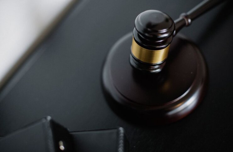From above of wooden gavel on round surface near folders on table in courtroom