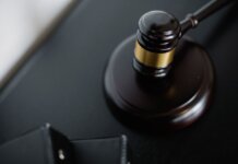 From above of wooden gavel on round surface near folders on table in courtroom