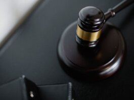 From above of wooden gavel on round surface near folders on table in courtroom