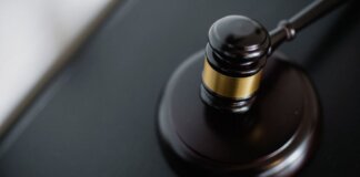 From above of wooden gavel on round surface near folders on table in courtroom