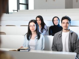 Group of diverse university students attending a class session in a modern lecture hall.