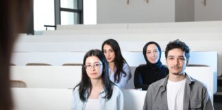 Group of diverse university students attending a class session in a modern lecture hall.