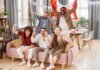 Group of friends cheering indoors with a Canadian flag, enjoying a lively moment together.
