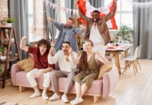 Group of friends cheering indoors with a Canadian flag, enjoying a lively moment together.