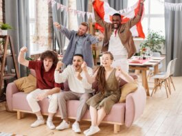 Group of friends cheering indoors with a Canadian flag, enjoying a lively moment together.