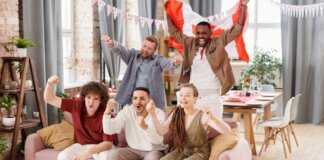 Group of friends cheering indoors with a Canadian flag, enjoying a lively moment together.