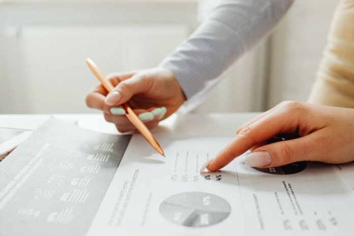 Hands holding a pencil, analyzing charts and data sheets, suggesting teamwork in an office setting. Hands holding a pencil, analyzing charts and data sheets, suggesting teamwork in an office setting.