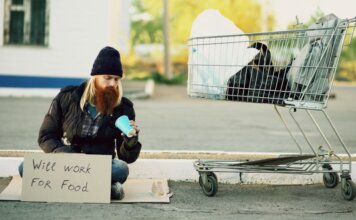 Консерваторы Канады: экономике нужно больше, чем рост на один квартал Homeless man sitting beside shopping cart with a sign "Will work for food."
