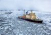 Icebreaker ship cutting through vast frozen ocean, showcasing winter exploration.
