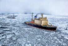 Icebreaker ship cutting through vast frozen ocean, showcasing winter exploration.