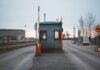 Пограничная служба изъяла более полутонны опиума, спрятанного в бумаге Industrial checkpoint and barrier at port under cloudy sky with cranes in the background.