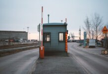 Пограничная служба изъяла более полутонны опиума, спрятанного в бумаге Industrial checkpoint and barrier at port under cloudy sky with cranes in the background.