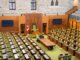Interior view of the Canadian House of Commons with green seating and wooden decor.