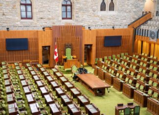 Interior view of the Canadian House of Commons with green seating and wooden decor.