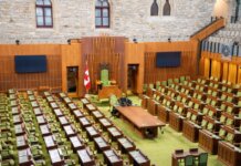 Interior view of the Canadian House of Commons with green seating and wooden decor.