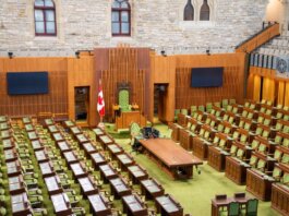Interior view of the Canadian House of Commons with green seating and wooden decor.