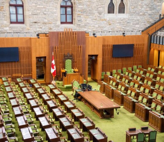 Interior view of the Canadian House of Commons with green seating and wooden decor.