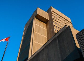 Low-angle shot of modern courthouse architecture with Canadian flag in London, Ontario.