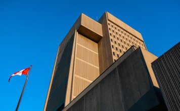Low-angle shot of modern courthouse architecture with Canadian flag in London, Ontario.