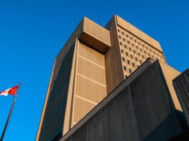 Low-angle shot of modern courthouse architecture with Canadian flag in London, Ontario.