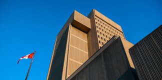 Low-angle shot of modern courthouse architecture with Canadian flag in London, Ontario.