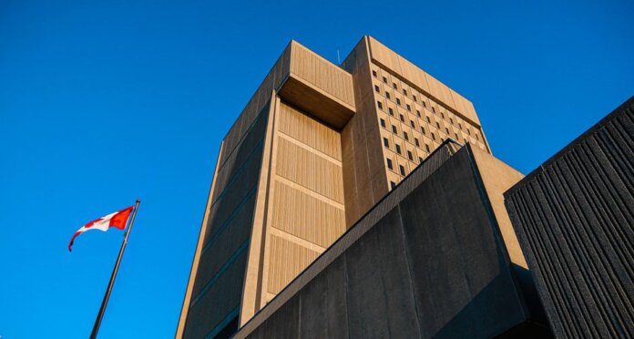Low-angle shot of modern courthouse architecture with Canadian flag in London, Ontario. Low-angle shot of modern courthouse architecture with Canadian flag in London, Ontario.